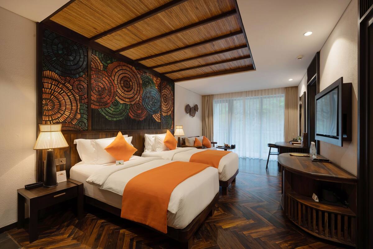 Une chambre d’hôtel avec deux lits, une télévision, un bureau et un grand mur décoratif.