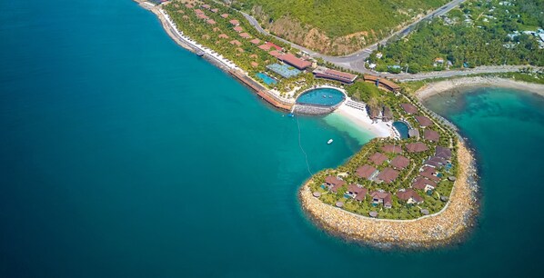 An aerial view of a coastal resort with a heart-shaped island, featuring multiple buildings, a swimming pool, and a beach. - Amiana Resort Nha Trang (Bac Nha Trang)