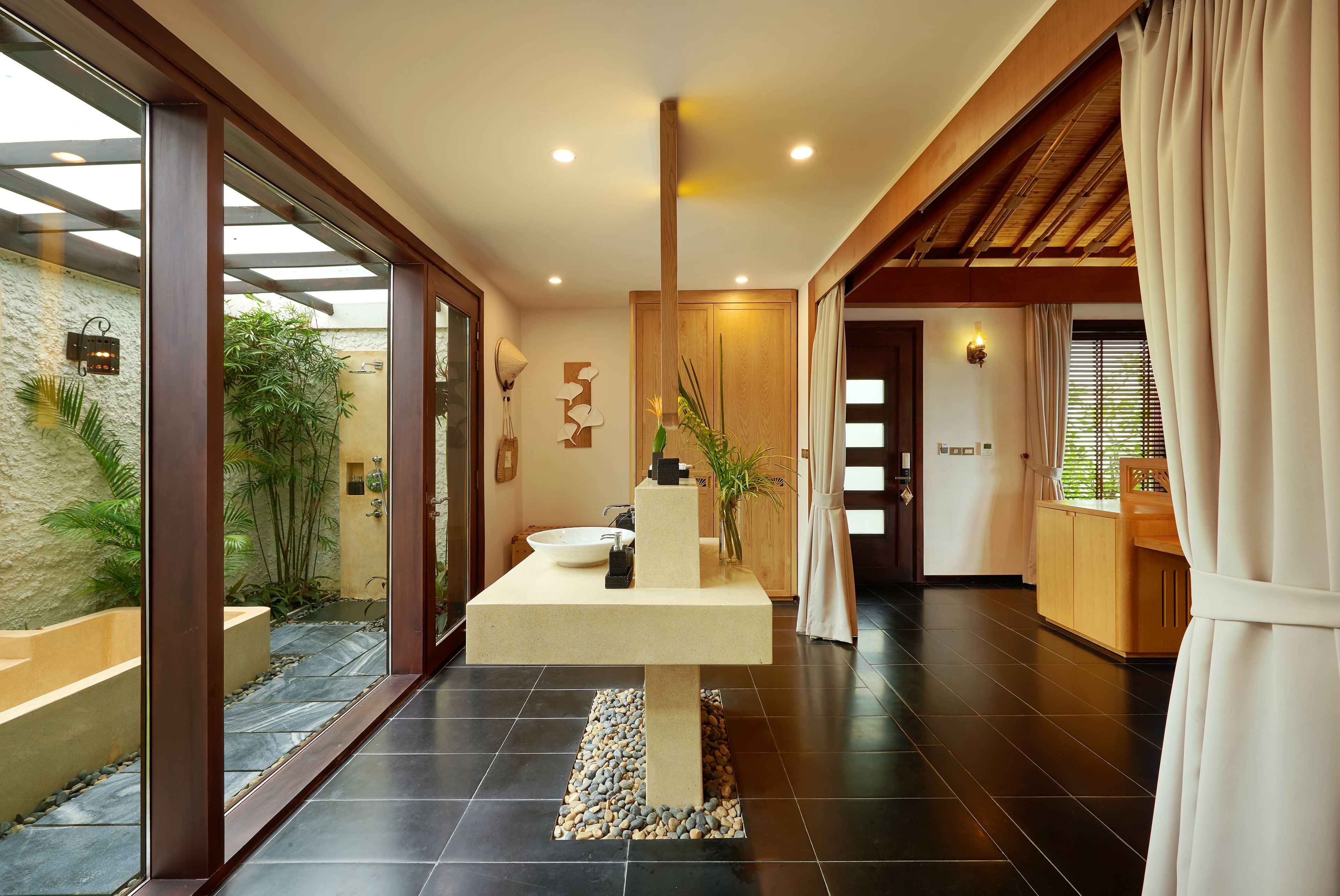 A modern bathroom with a large bathtub, a sink, and a decorative plant.