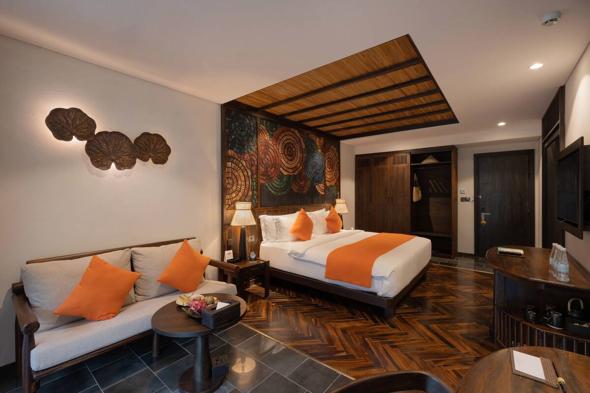 Une chambre d’hôtel avec deux lits, un canapé, une petite table et un élément décoratif mural.