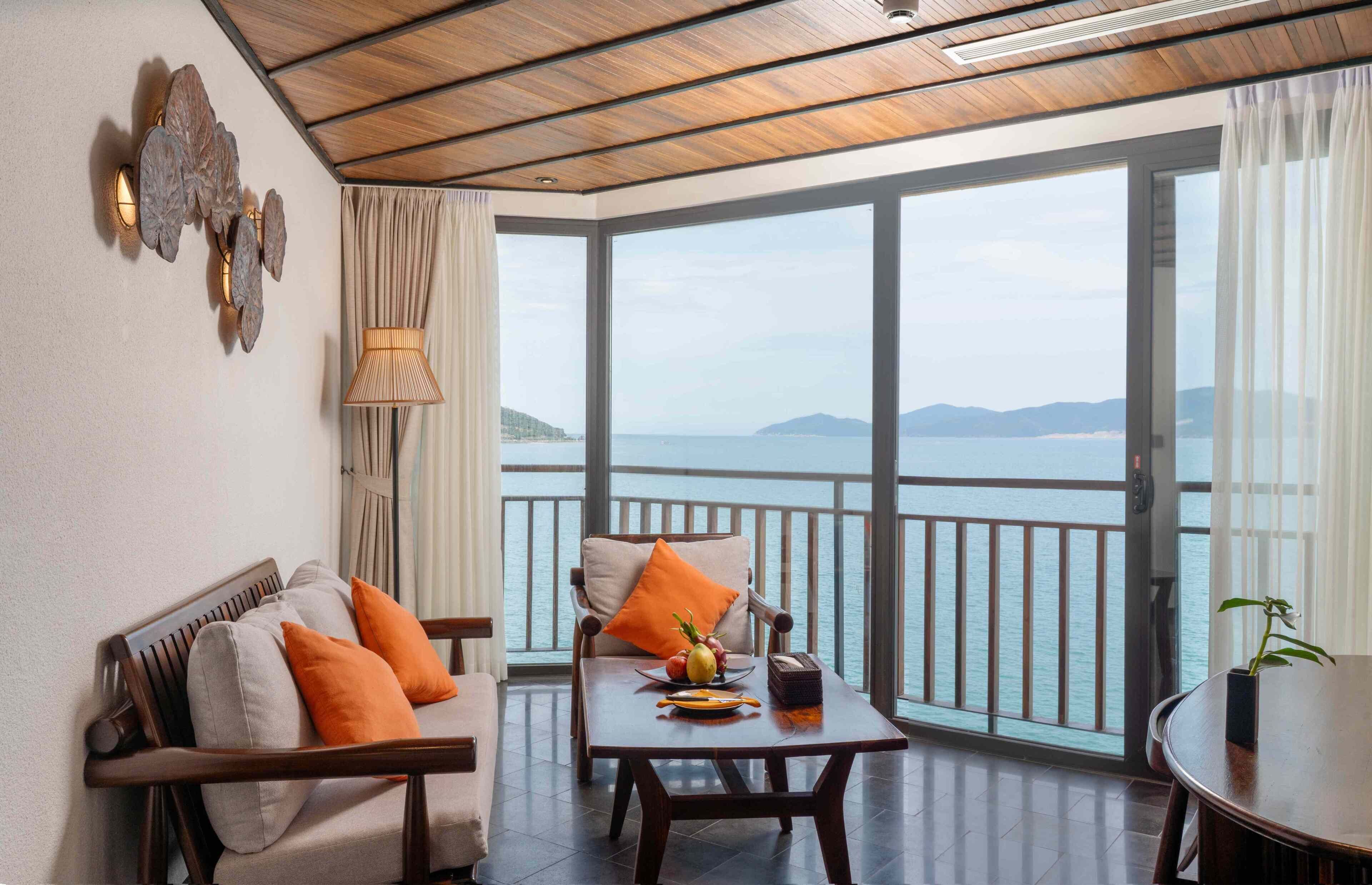 Ein Balkon mit Meerblick, eine Couch, ein Tisch mit Obstschale und eine Lampe.