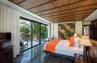 A spacious bedroom with a large bed, a TV, and a balcony with outdoor seating.