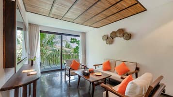 Ein modernes Zimmer mit einer Couch, Stühlen, einem Tisch und einem Balkon mit Blick auf Grünfläche.