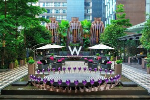 A courtyard with a central seating area, surrounded by greenery and modern buildings in the background.