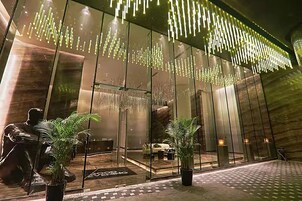 A modern hotel lobby with reflective glass walls, a central seating area, and decorative lighting.