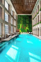 Una piscina con pared verde y zona de estar.