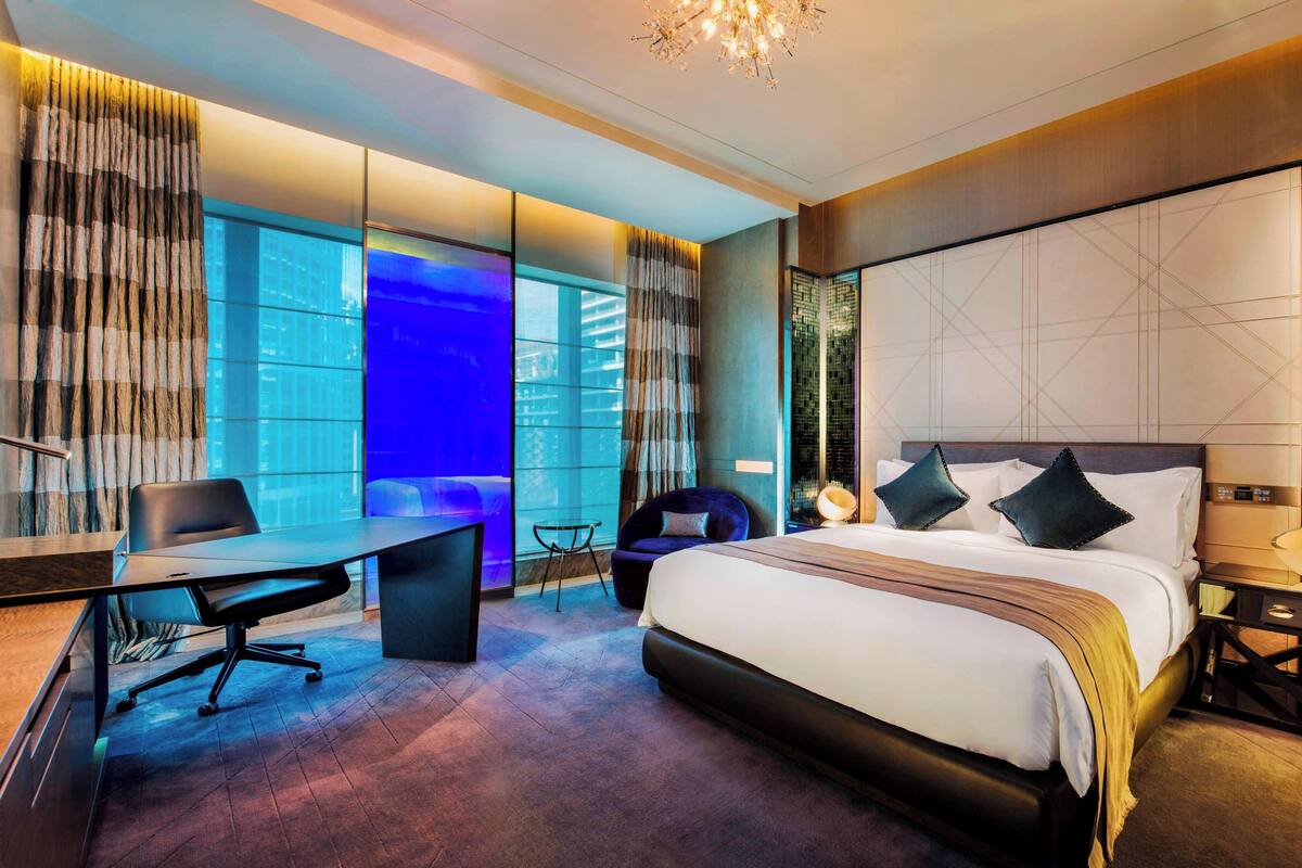 Une chambre d’hôtel moderne, dotée d’un grand lit, d’un bureau et d’une chaise.