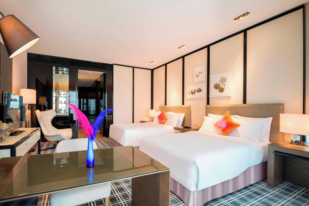 Une chambre d’hôtel avec deux lits, un bureau, une chaise et un miroir.