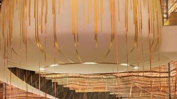 A lobby with a circular seating area, a staircase, and hanging decorative elements.
