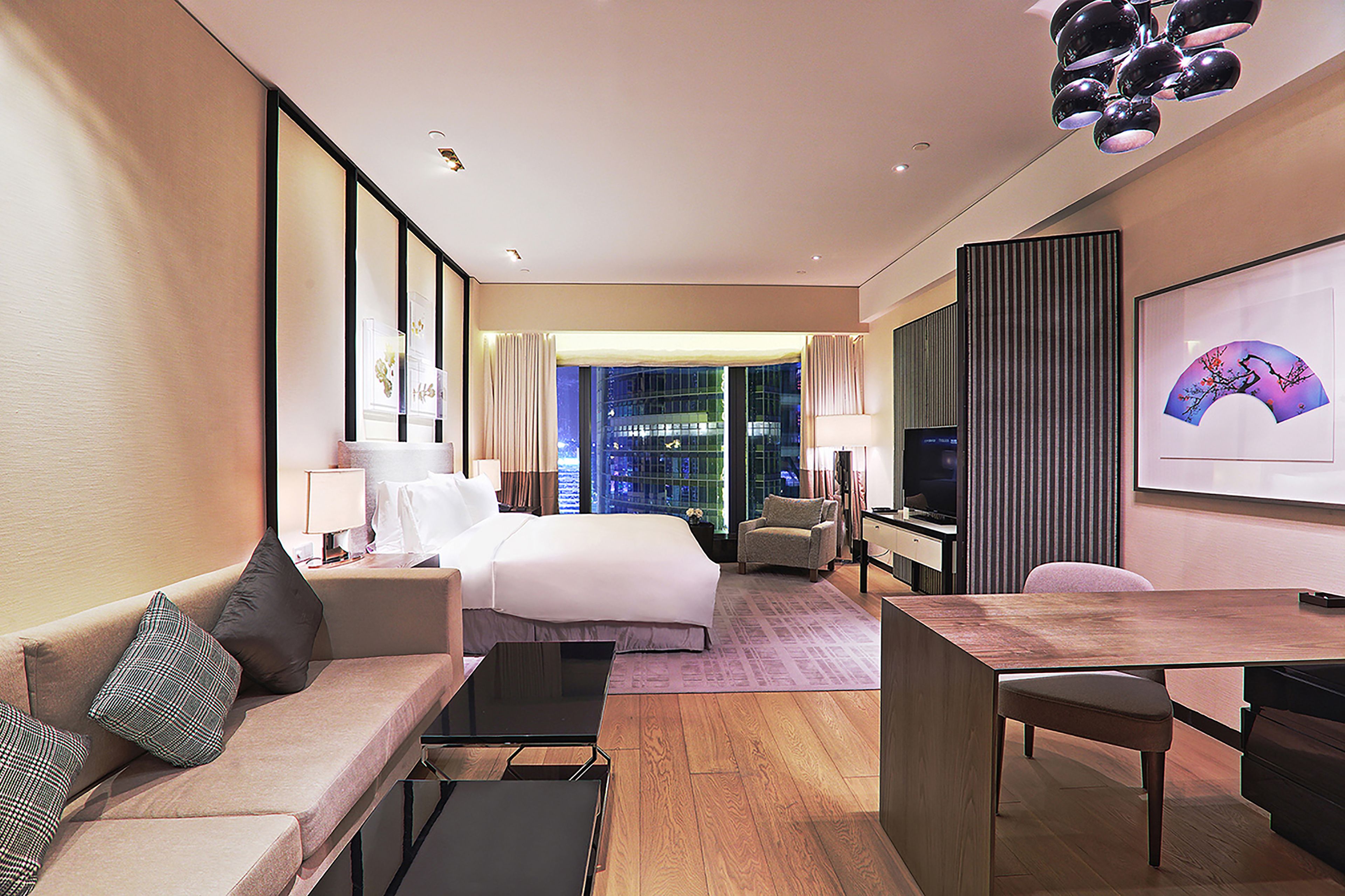 A hotel room with a bed, a sofa, a desk, and a television.