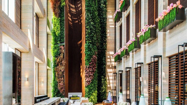Un espacio interior amplio con techo alto, muebles modernos y jardines verticales.