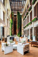 A spacious indoor area with a high ceiling, modern furniture, and vertical gardens.