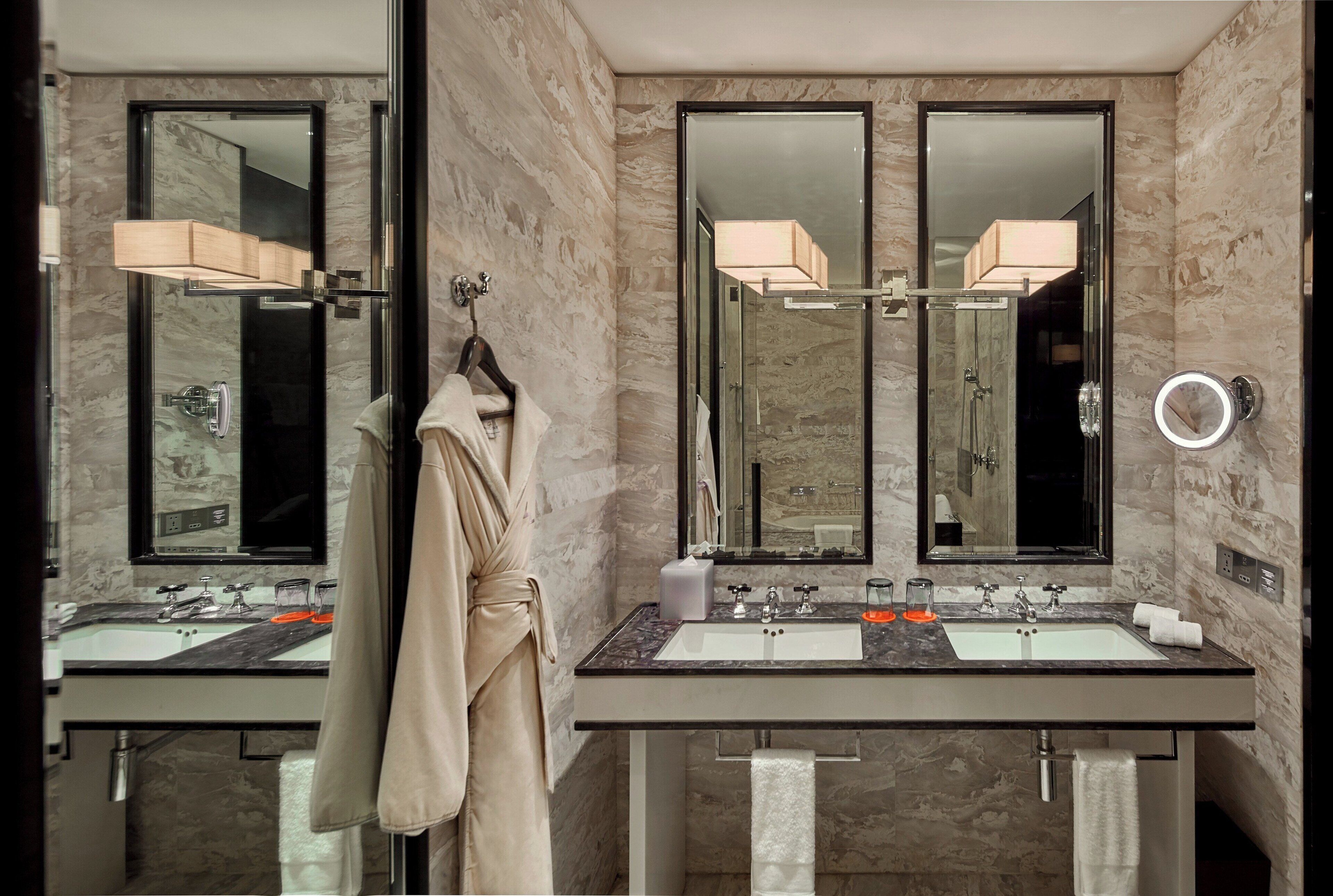 Un bagno moderno con due lavabi, un accappatoio appeso e un grande specchio.