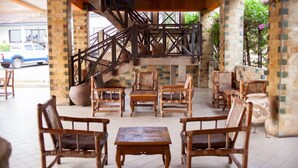 A covered outdoor seating area with wooden furniture and a staircase leading to an upper level. - Rexmar Hotel (Kumasi)