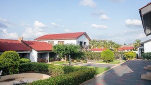 A residential area with houses having red roofs, a paved driveway, and well-maintained gardens. - Rexmar Hotel (Kumasi)