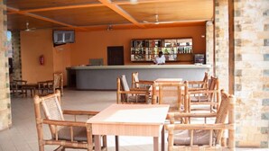 A restaurant with wooden furniture and a bar area. - Rexmar Hotel (Kumasi)