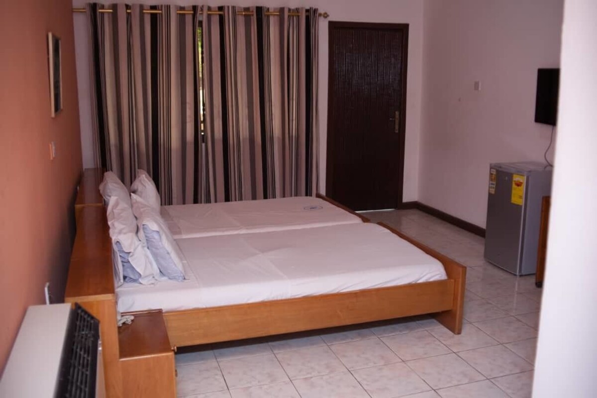 A room with a double bed, a small desk, a television, and a door.