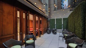 An outdoor seating area with wicker furniture and a green hedge wall. - Best Western Premier Herald Square (New York)