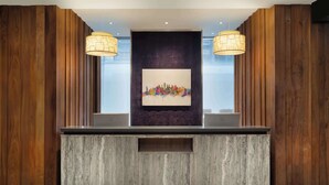 A reception desk with a modern design, featuring a wooden panel backdrop and a central artwork. - Best Western Premier Herald Square (New York)