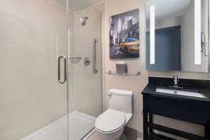 A modern bathroom with a glass shower enclosure, a white toilet, a black sink, and a mirror with a cityscape picture. - Best Western Premier Herald Square (New York)