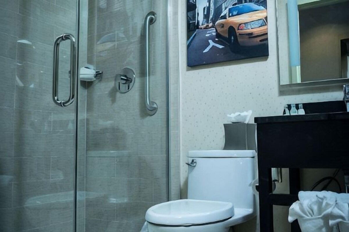 A bathroom with a glass shower enclosure, a white toilet, and a black sink with a mirror above.