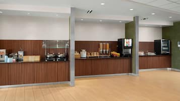 A modern hotel lobby with a wooden reception desk, a coffee machine, and a self-service beverage station.