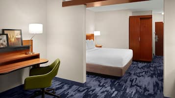 A hotel room with a bed, desk, chair, and a wardrobe.