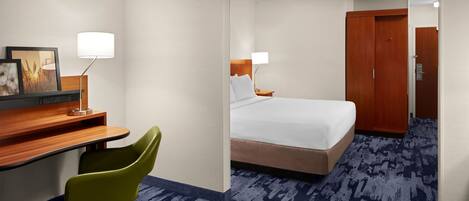A hotel room with a bed, desk, chair, and a wardrobe.