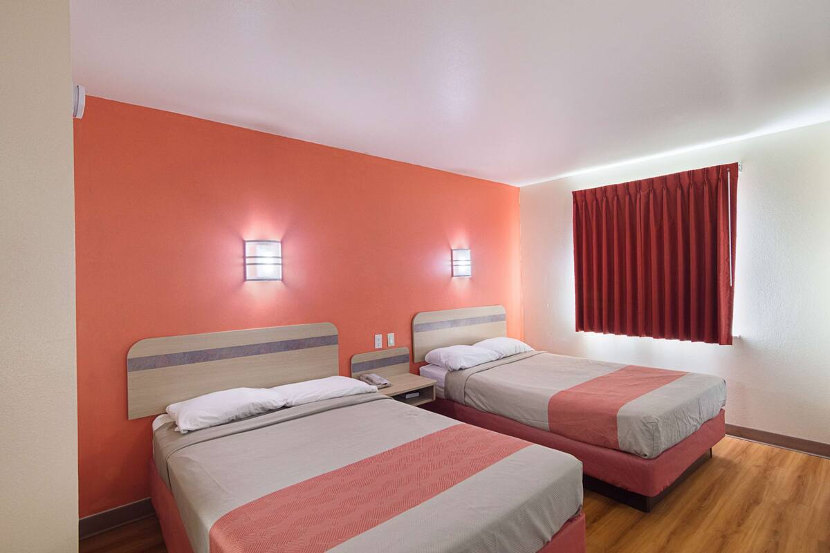Habitación de hotel con dos camas, cada una con cabecero y mesitas de noche.