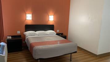 Una habitación de hotel con una cama, dos mesitas de noche y una lámpara de pared.
