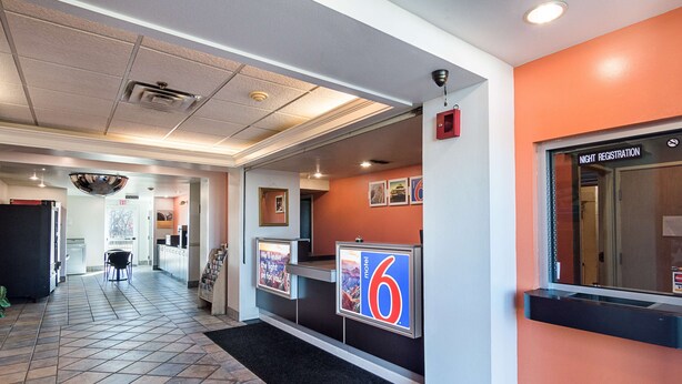 A hotel reception area with a tiled floor, a reception desk, and a sign for night registration. - Motel 6 Terrell, TX (Terrell)