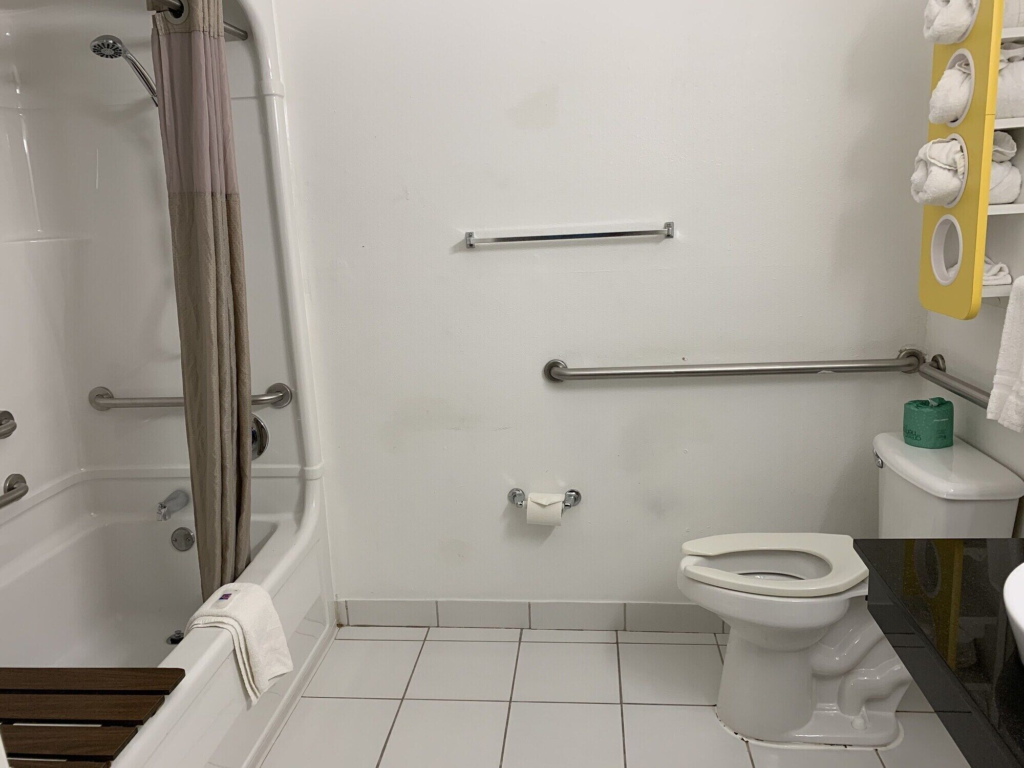 Een badkamer met een bad, toilet en handgrepen.