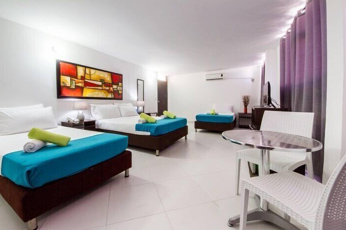 A hotel room with two beds, a small table, and a chair.