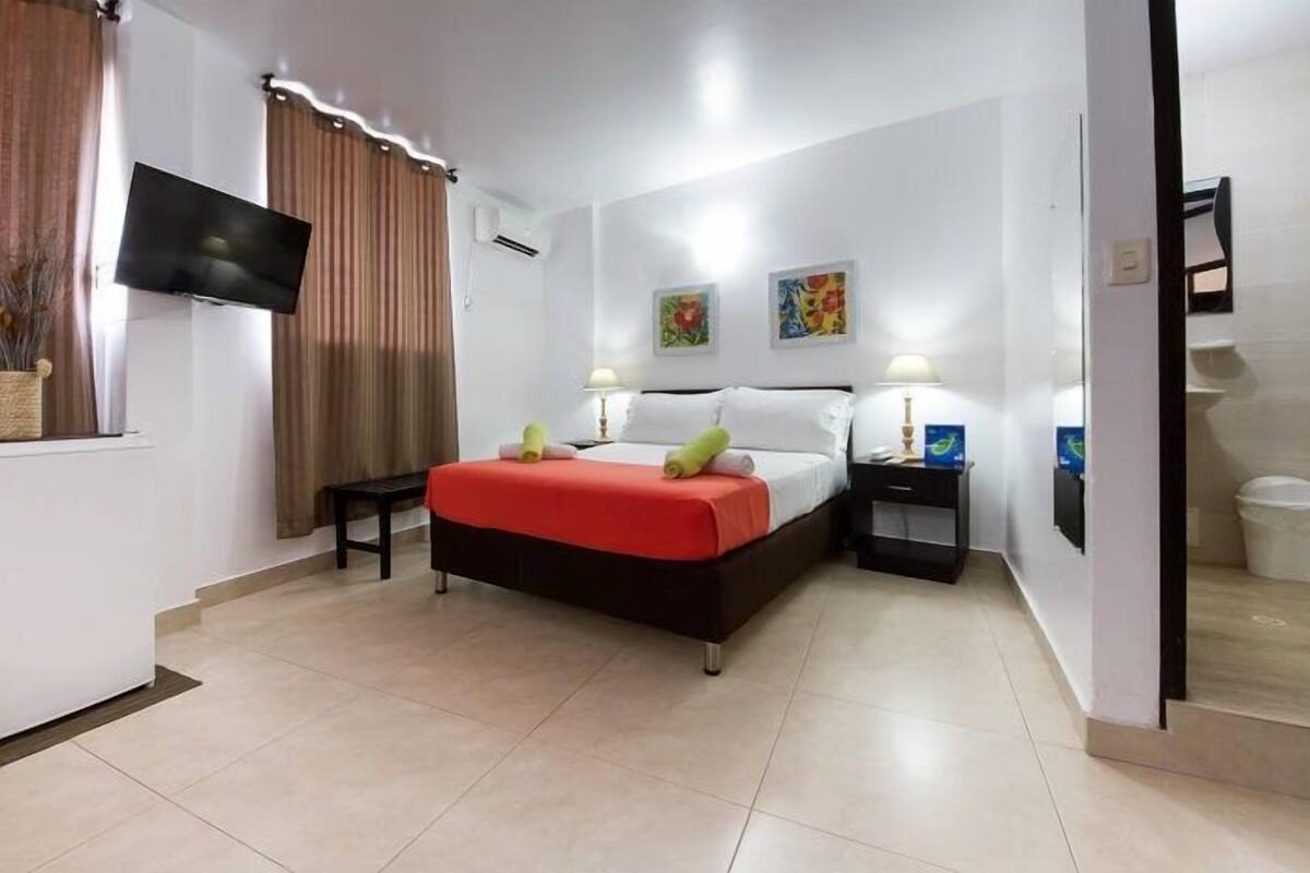 A hotel room with a bed, a TV, a desk, and a bathroom.