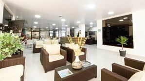 Un hall con mobiliario de mimbre, una mesa de recepción y una planta en maceta.