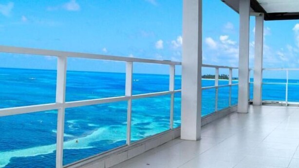 Un balcón amplio con vista despejada al océano y una isla distante.
