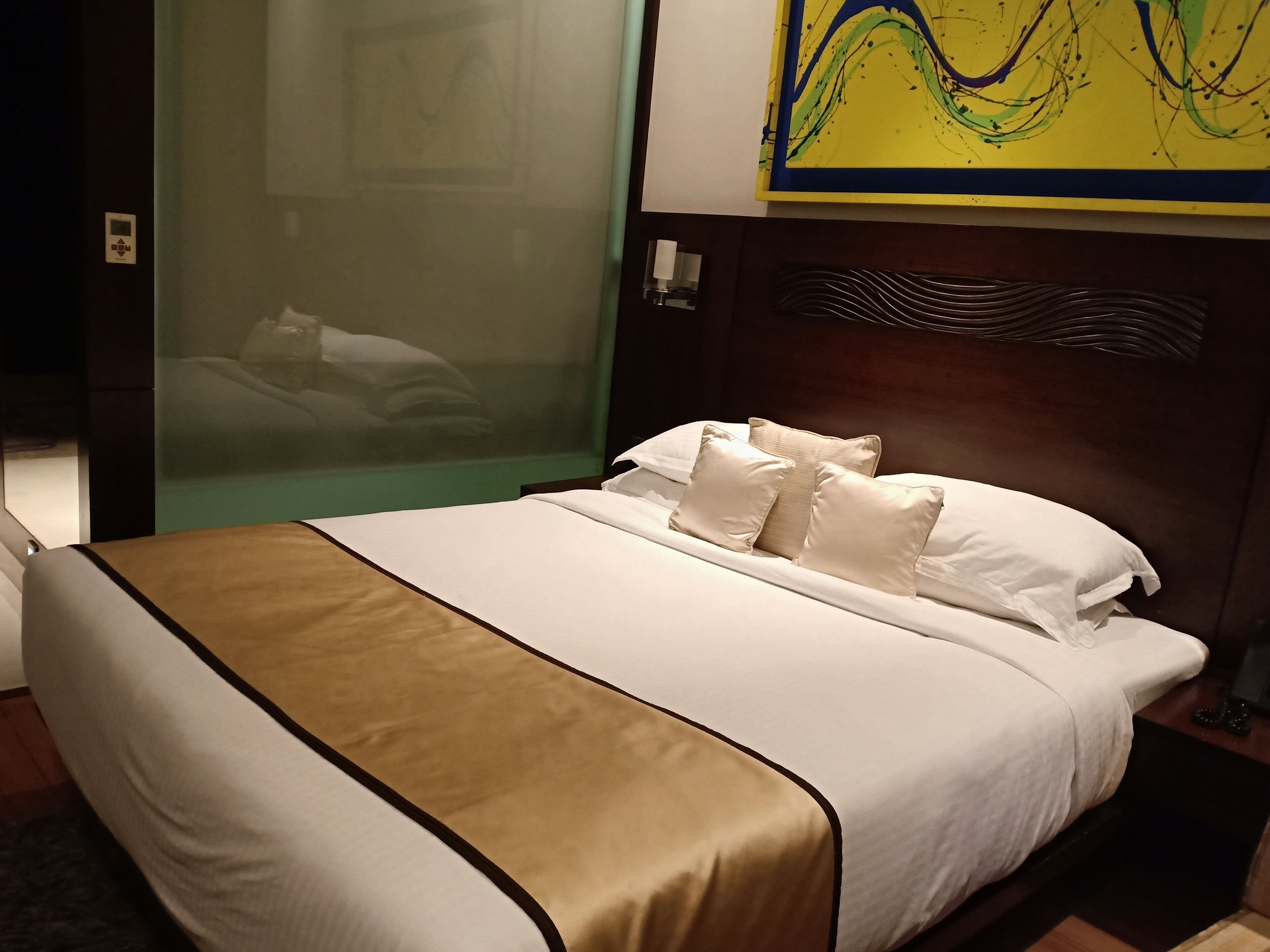 Quarto de hotel com cama, mesa de cabeceira, uma obra de arte na parede e janela com vista.