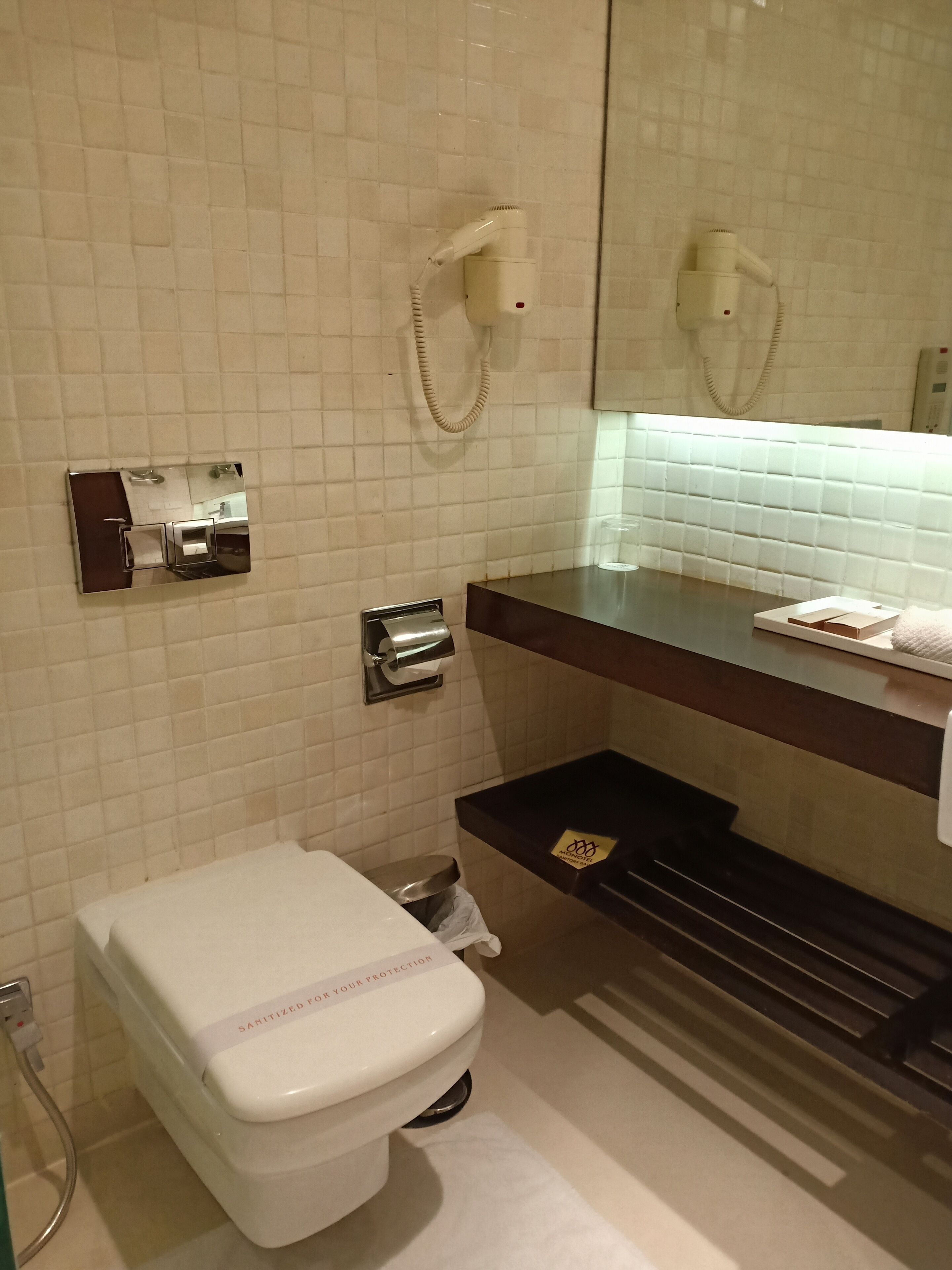 Une salle de bain équipée d’un WC blanc, d’un sèche-mains, d’un distributeur d’essuie-tout et d’une poubelle.