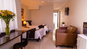 Une chambre d’hôtel comprenant un lit, un bureau avec une chaise, un canapé et un téléviseur.