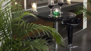 Un espace repas moderne avec une table ronde noire, des bougies et des verres à vin.