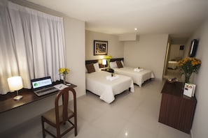 A hotel room with two beds, a desk with a laptop, a chair, a desk lamp, and a vase with flowers. - El Angolo Lima (Lima)