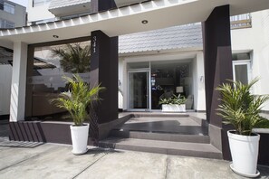 A modern building entrance with a glass door, potted plants, and a number '341' sign. - El Angolo Lima (Lima)