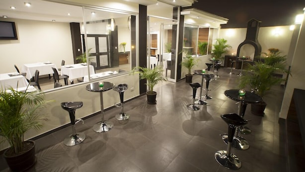 Un espace de restauration extérieur moderne, doté de plusieurs tables et chaises, et agrémenté de plantes en pot.