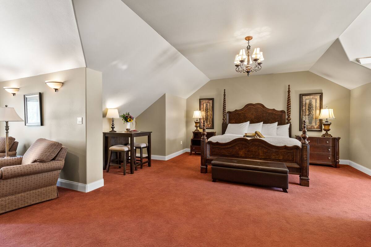 A bedroom with a large bed, a desk, and a chair.