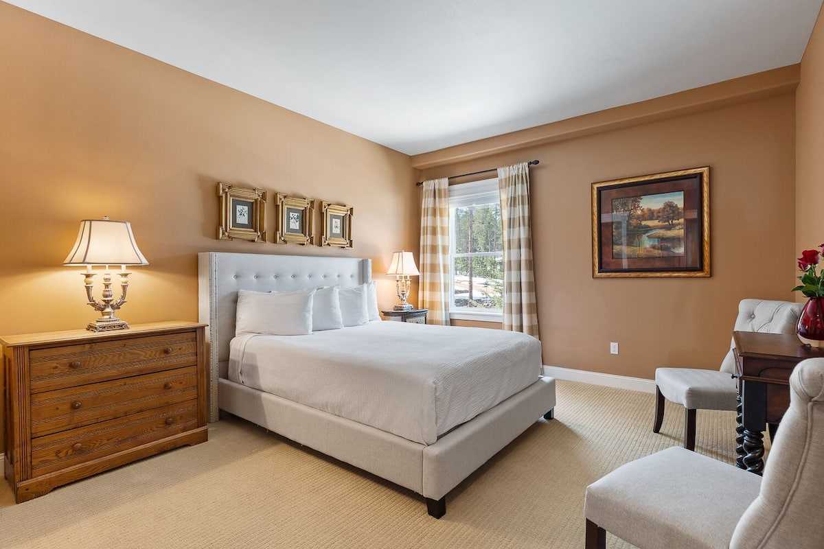 A hotel room with a large bed, wooden nightstands, a desk, and a chair.