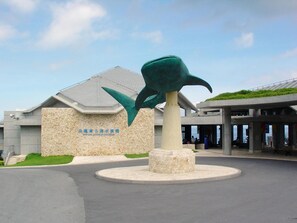A building with a stone facade and a large green sculpture in front.