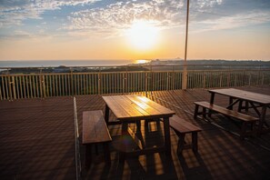 A wooden deck with picnic tables and a railing overlooking a scenic view.