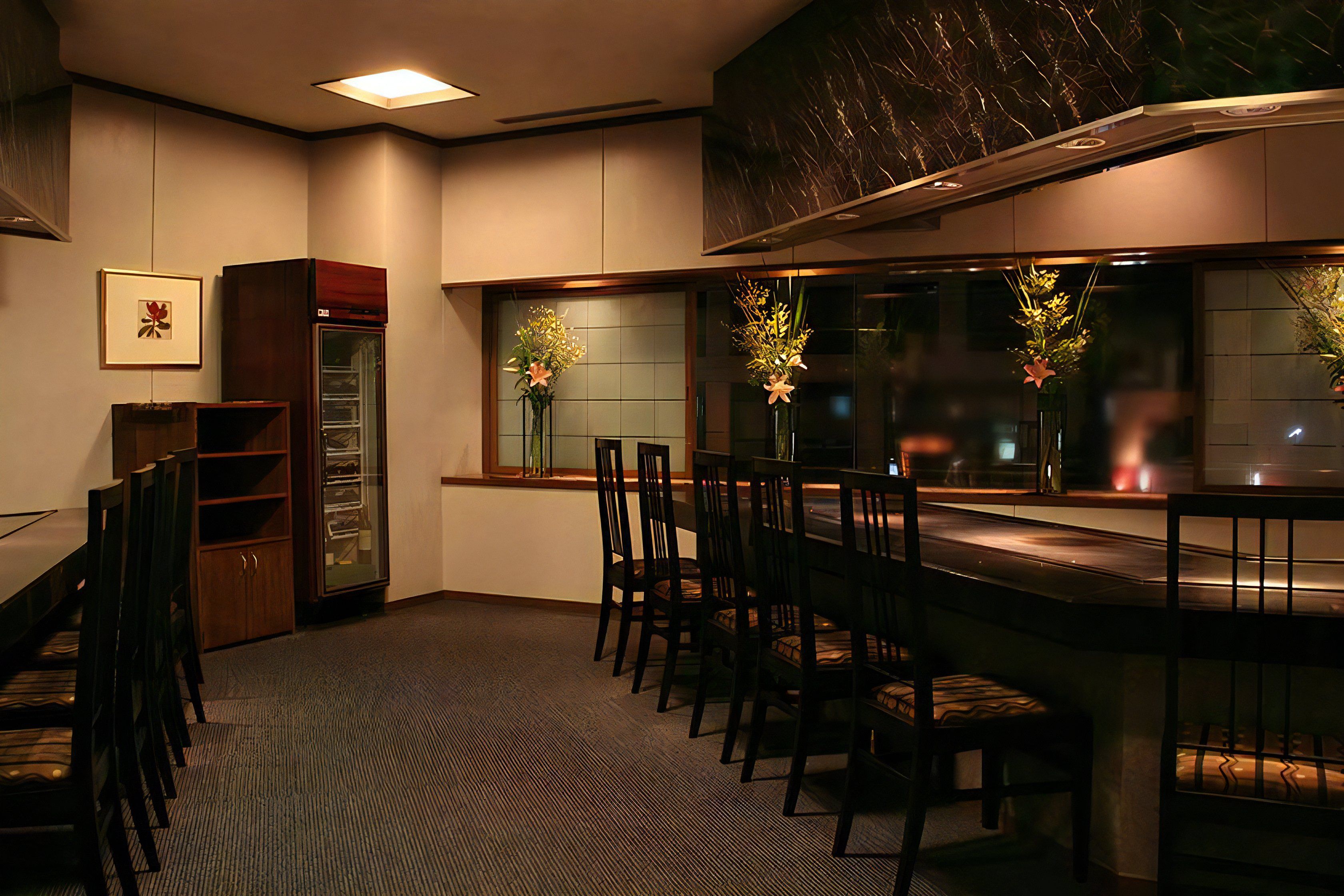 A restaurant with a long counter, multiple chairs, and a glass display case.