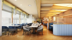 Een modern restaurant met houten vloeren, blauwe gestoffeerde stoelen en een centrale eettafel.