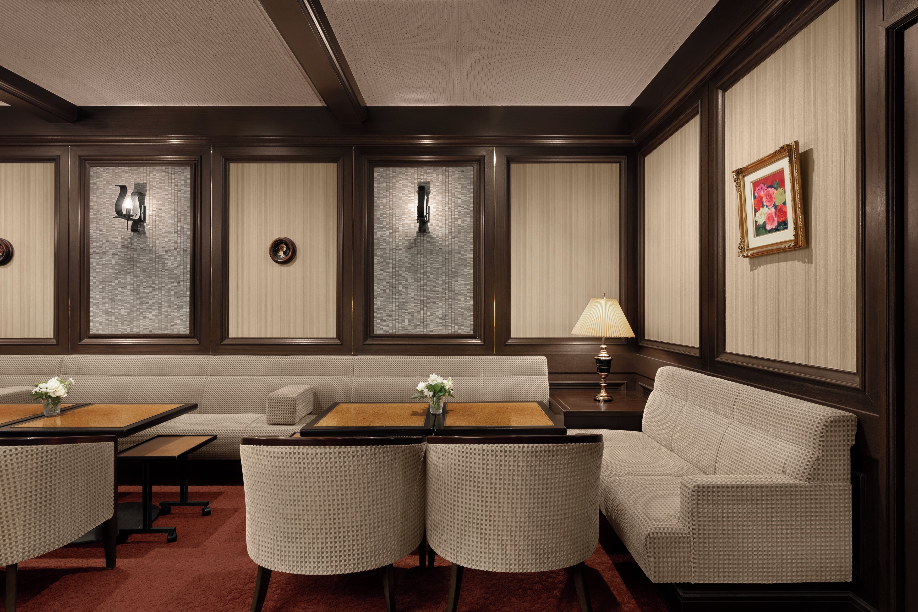 A hotel lobby with a seating area, tables, and a lamp.